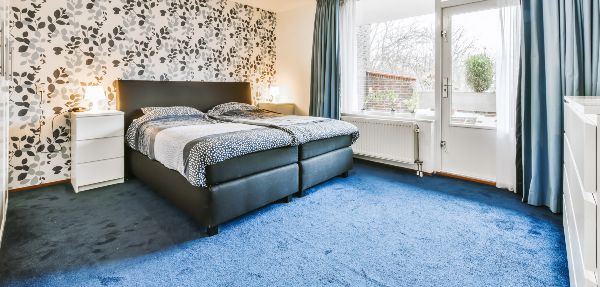 Stylish bedroom with blue carpet and floral wallpaper