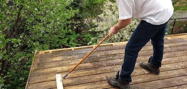 Person sweeping wooden deck.