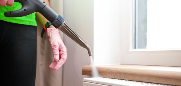 Person cleaning a radiator with a steam cleaner.