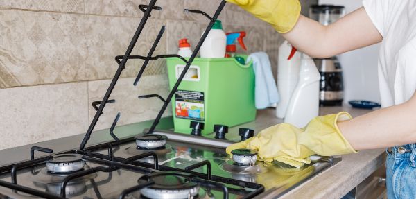 Person cleaning a stove while wearing gloves