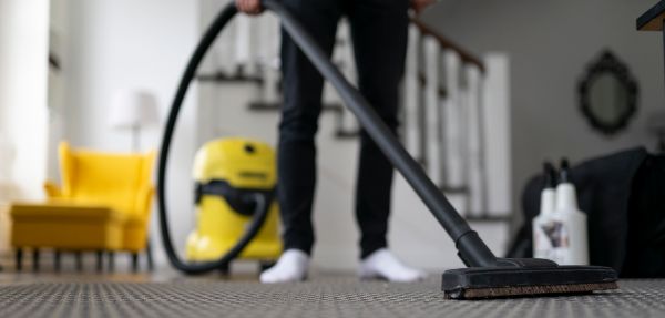 Man vacuuming the carpet in the room. 