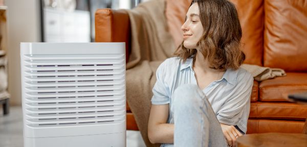 Woman sitting next to an air purifier.