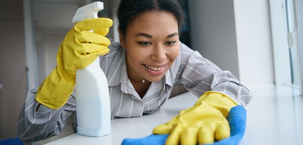 Woman with gloves on cleaning countertop.