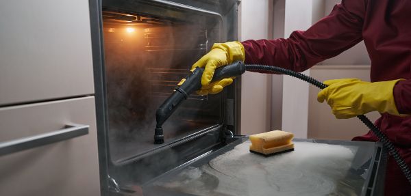 Person steam cleaning an oven.