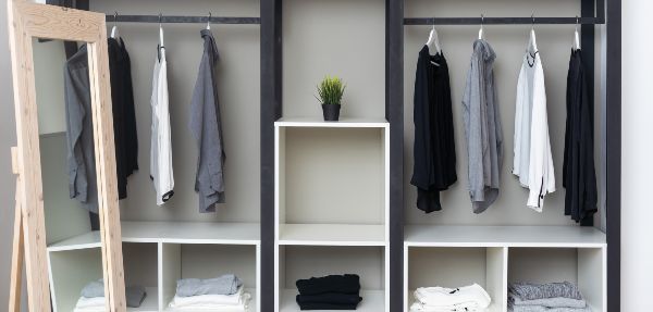 Clothes hanging in an open wardrobe in a bedroom.