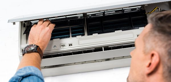 Close up view of man fixing filter of air conditioner