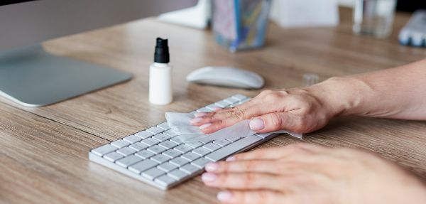 Woman cleaning keyboard in the office.