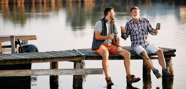 Happy man and his father having fun while relaxing on a pier and fishing together. 