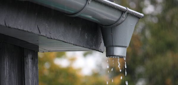 Water dripping through the opening in a roof gutter.