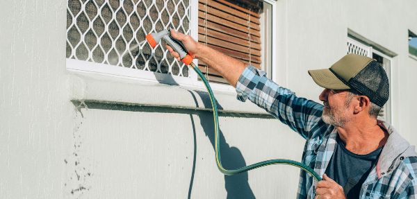 Man cleaning windows with a hose.