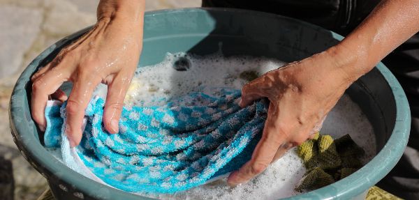 Person handwashing clothes in a bucket.