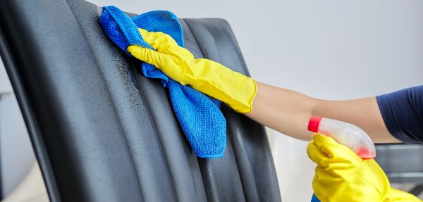 Close-up of a woman cleaning a leather chair.