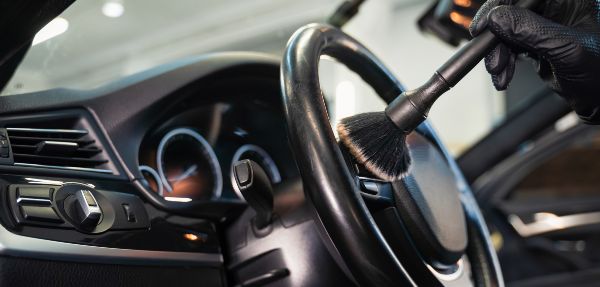 Professional car cleaning. Cleaning the steering wheel of a car from dirt with a brush.