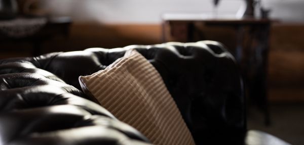 Close-up of a leather couch with a pillow on it.