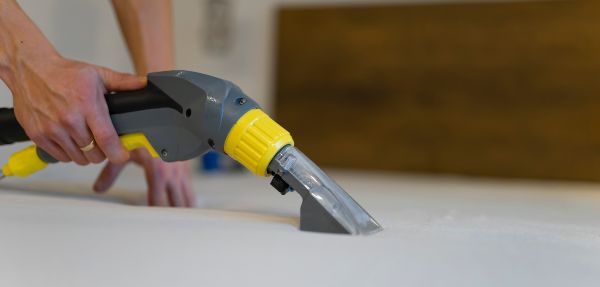 Close-up shot of a person vacuuming a mattress.