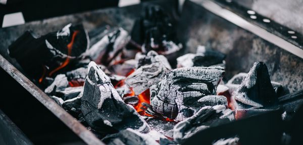 Selective focus of hot burning coals with ash in iron BBQ grill