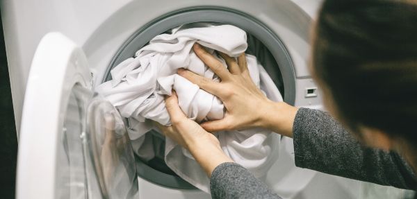 Person washing their bedding in a washing machine.