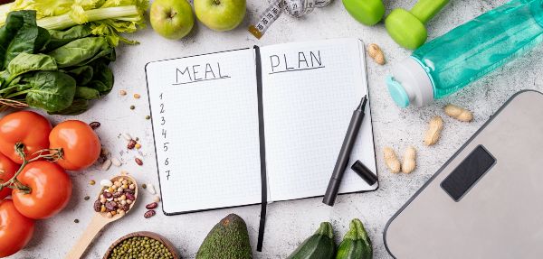 Meal planning book with various foods around it.