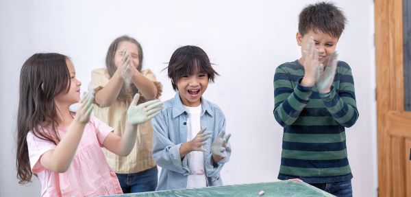 Children with dusty hands enjoying themselves while playing with chalk.