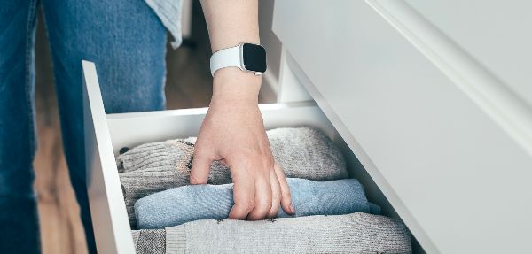 Close-up of a person's hand grabbing an item of clothing from a clothes drawer.