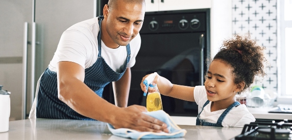 Father and daughter cleaning a kitchen surface together