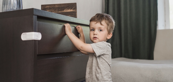 Little boy standing next to a clothes drawer