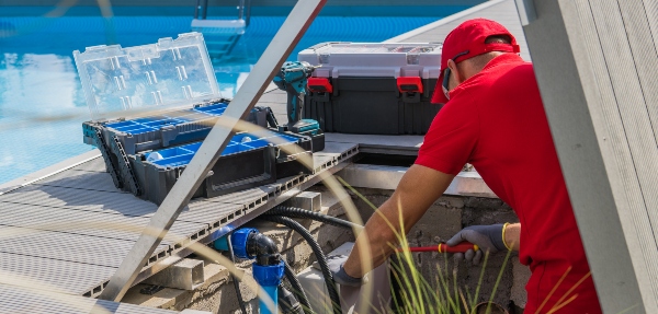 Closeup of a Professional Worker in Red Uniform Fixing an Outdoor Swimming Pool Heating System.