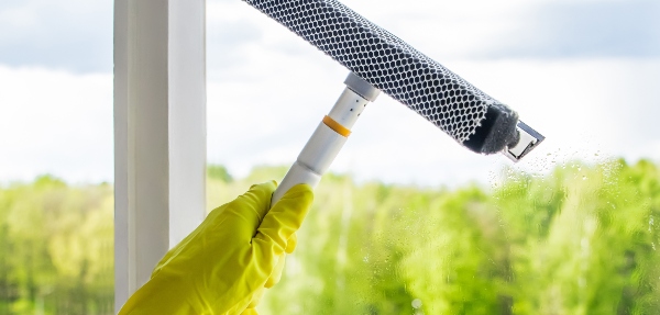 Close-up of a hand holding a squeegee and cleaning a window