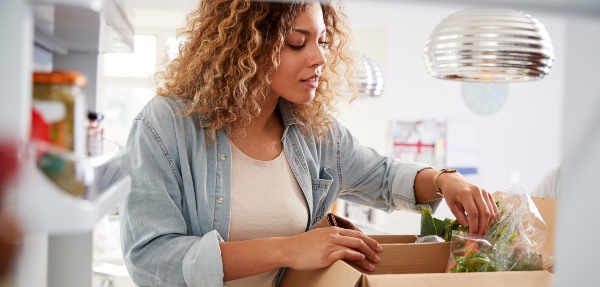 Woman packing groceries inside her fridge