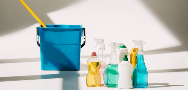 Various cleaning products and a mop and bucket on white floor