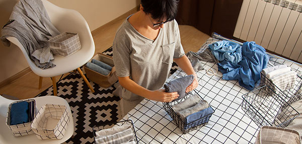 A woman folding clothing in her home.