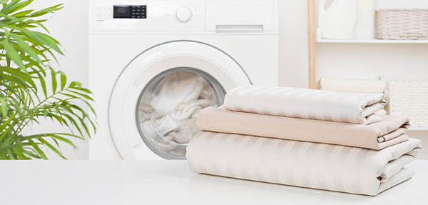 Clean folded linen in front of a washing machine