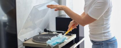 Person cleaning a record player with a duster.