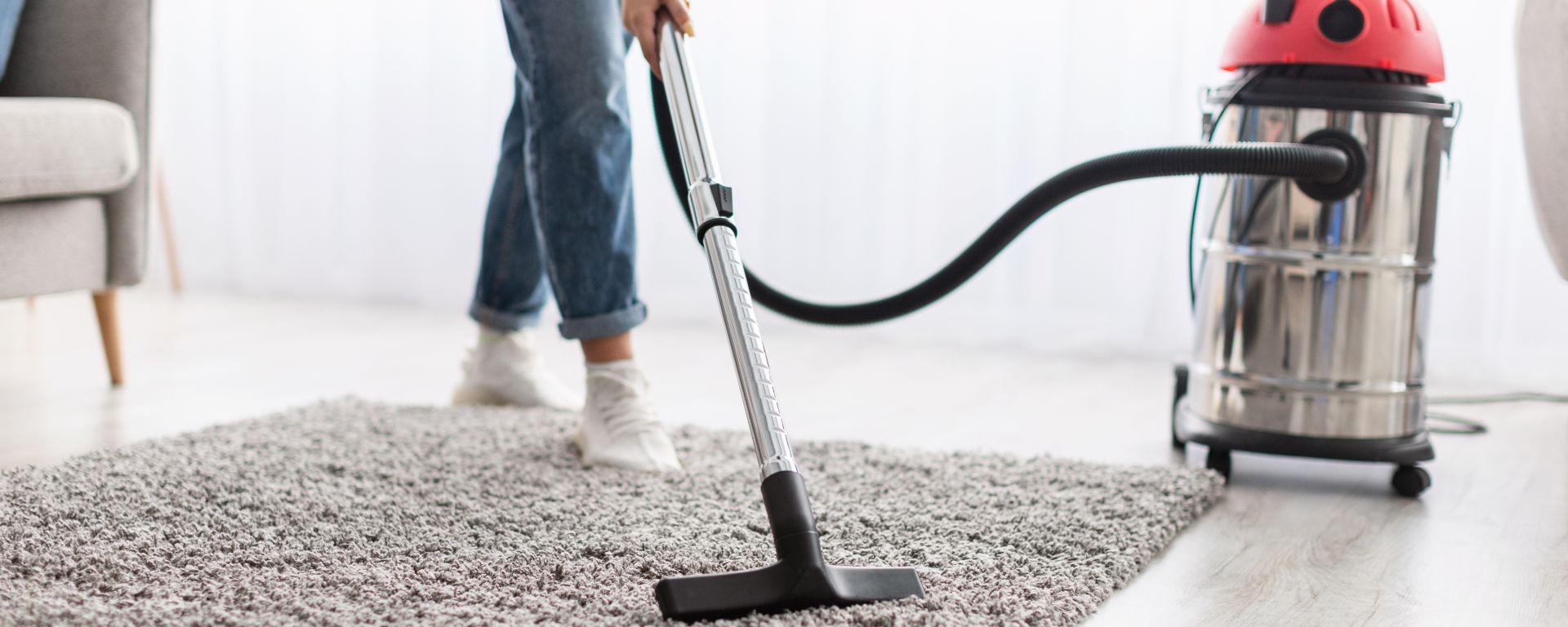 Person cleaning carpet with vacuum cleaner.