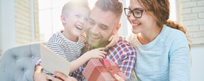 Family smiling as dad holds and reads card