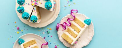 Top view of a birthday cake with slices cut from it and put on two other plates