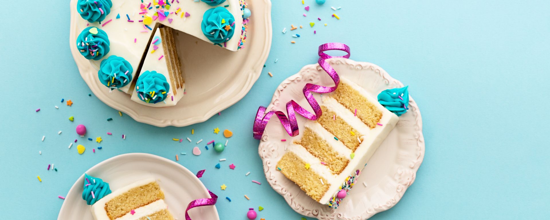 Top view of a birthday cake with slices cut from it and put on two other plates