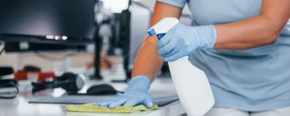 Close up view of woman in protective gloves cleaning tables in the office.