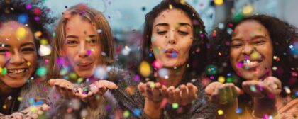 Four women blowing confetti out into mid air