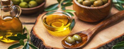 Organic olive oil in a bowl with green olives.