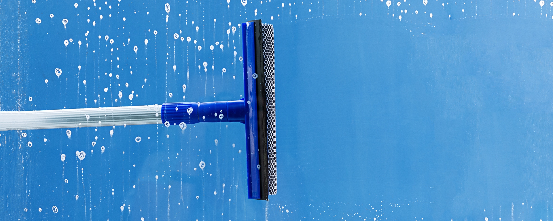 Rubber squeegee cleans a window. Clears a stripe of soapy window.