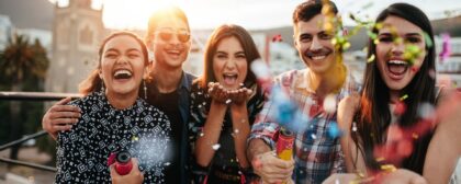 Friends celebrating outside together while popping confetti