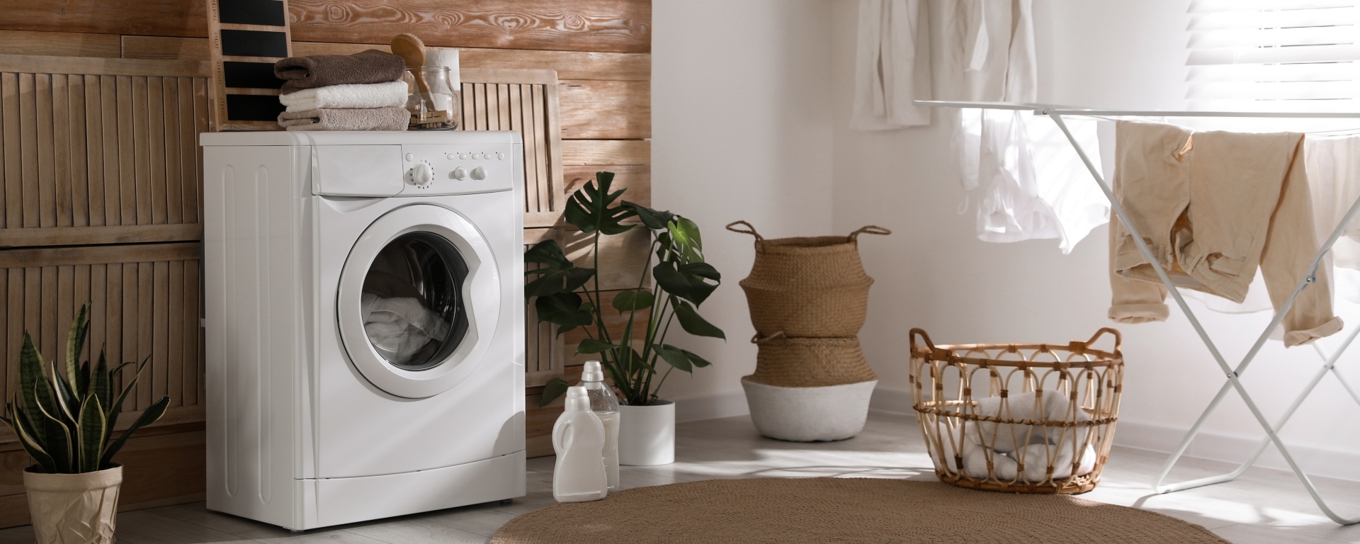 Laundry room setup with washing machine, washing baskets, and clothes horse with clothes hanging on it