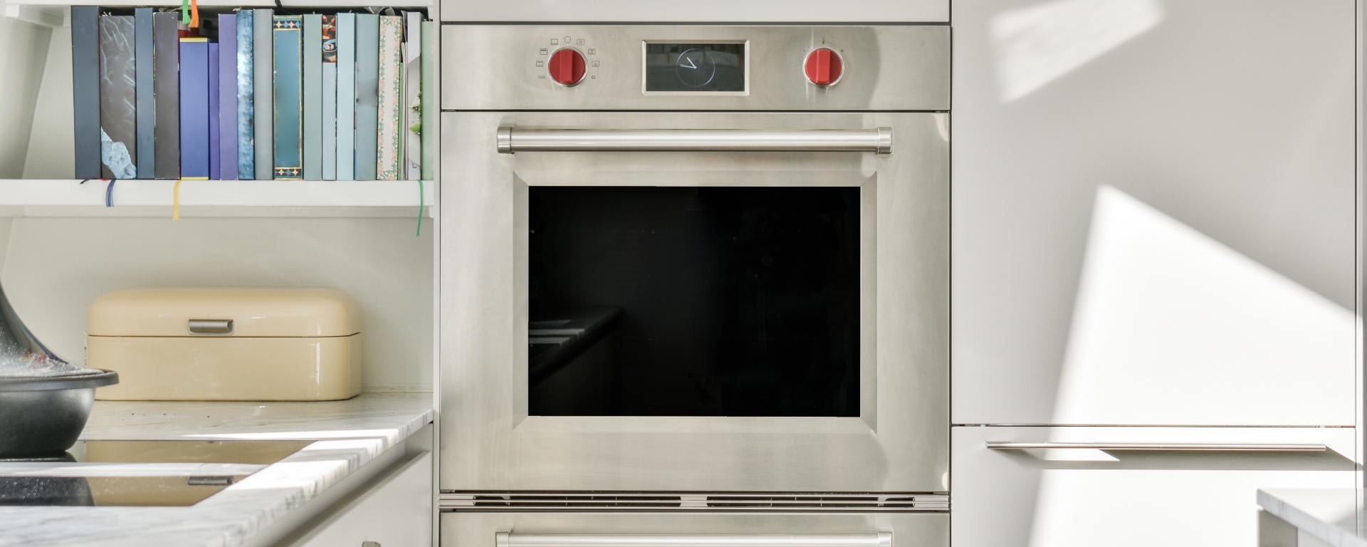 Modern oven built into the kitchen unit with shelves with books beside