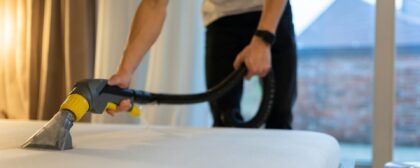 Close-up shot of a man vacuuming a mattress